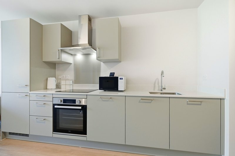 Modern kitchen with cream cabinetry, stainless steel appliances, and integrated cooker hood