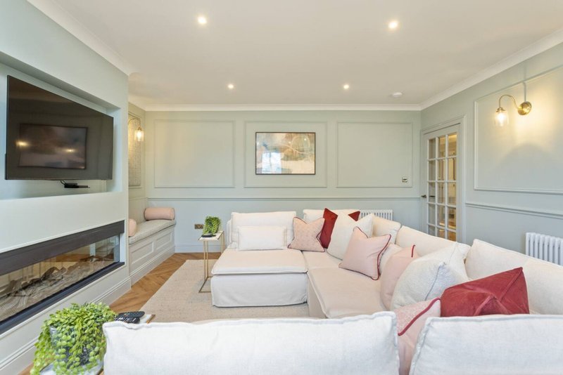 Modern living room with cream sofa, fireplace, wall-mounted TV and recessed ceiling lights
