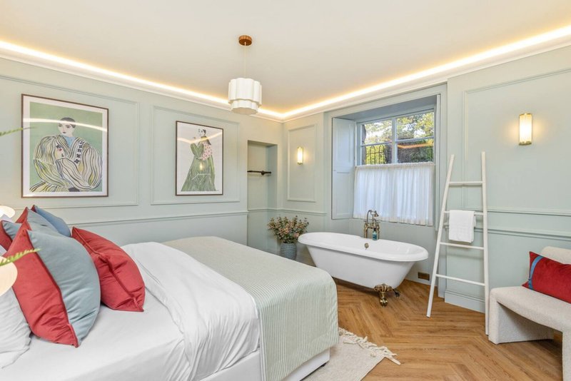 Bedroom with double bed, en-suite bathroom, framed artwork, and natural light from windows