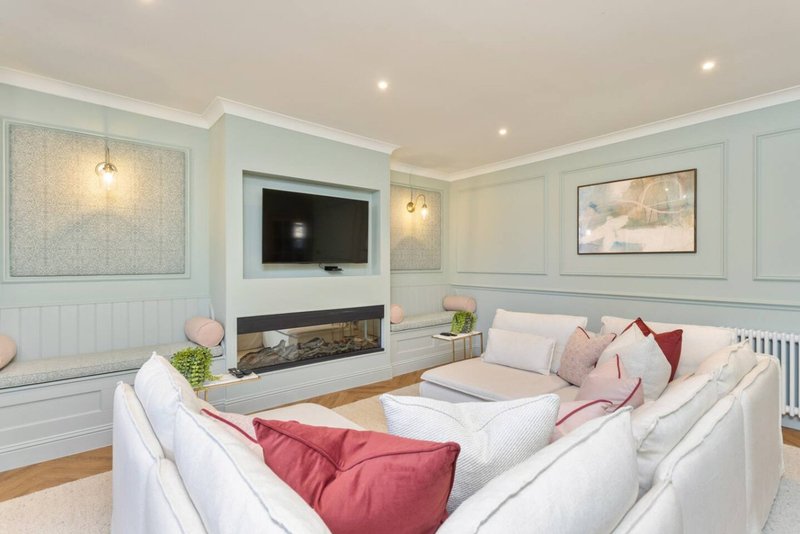 Modern living room with white sectional sofa, fireplace, wall-mounted TV and recessed lighting
