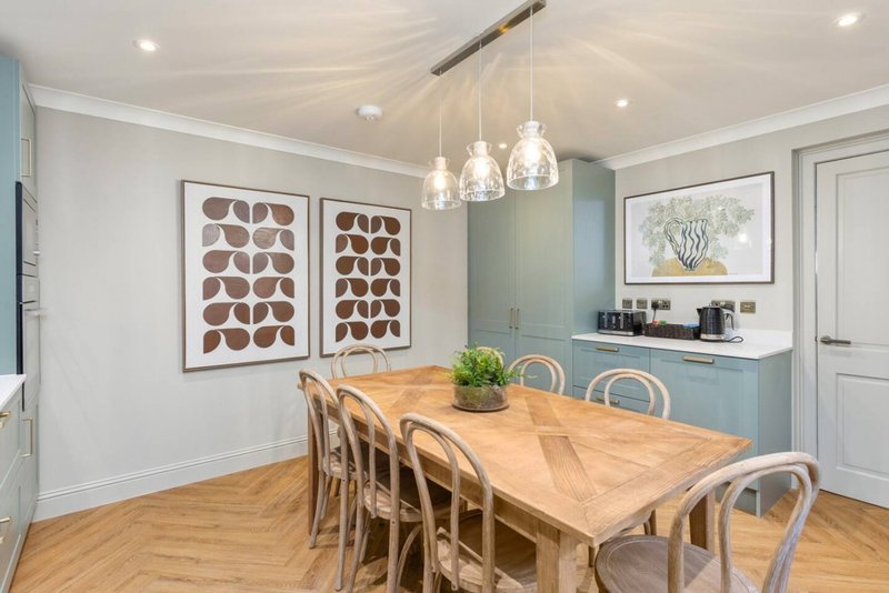 Modern dining room with wooden table, rattan chairs, pendant lights and framed wall art
