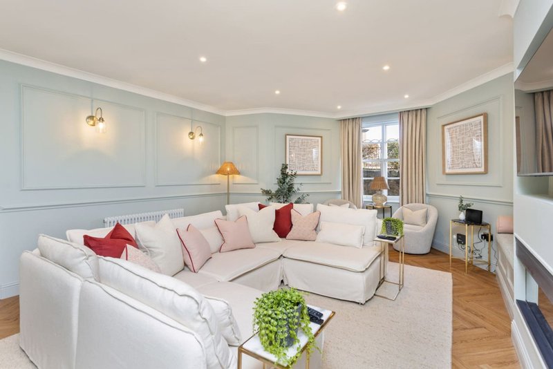 Spacious living room with white sectional sofa, decorative cushions, pendant lights, and garden view