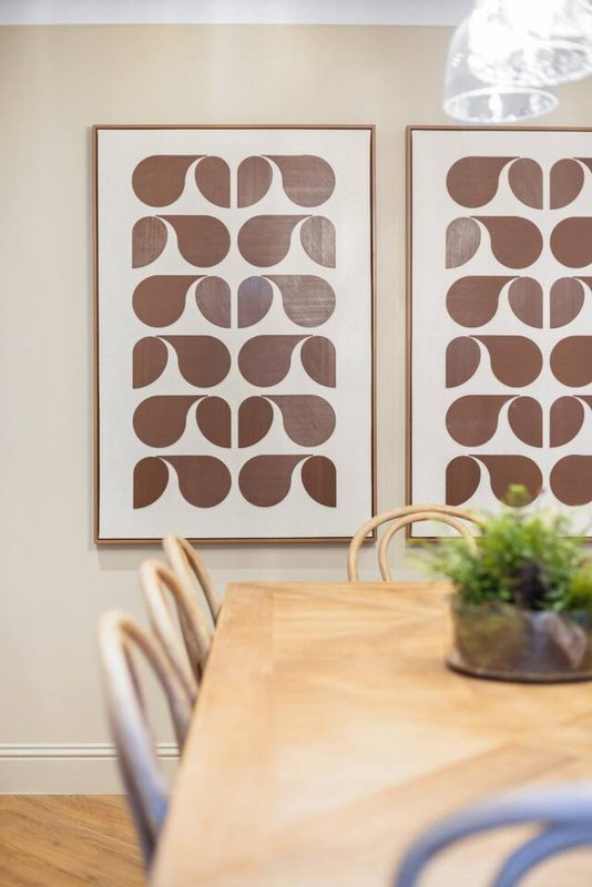 Dining area with wooden table, chairs, and framed geometric wall art above