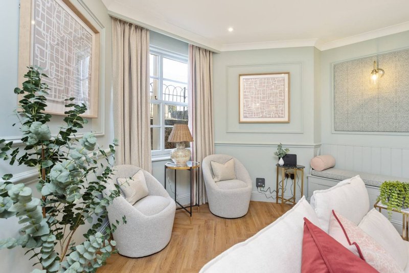 Modern living room with cream armchairs, white sofa, wooden floor and large windows