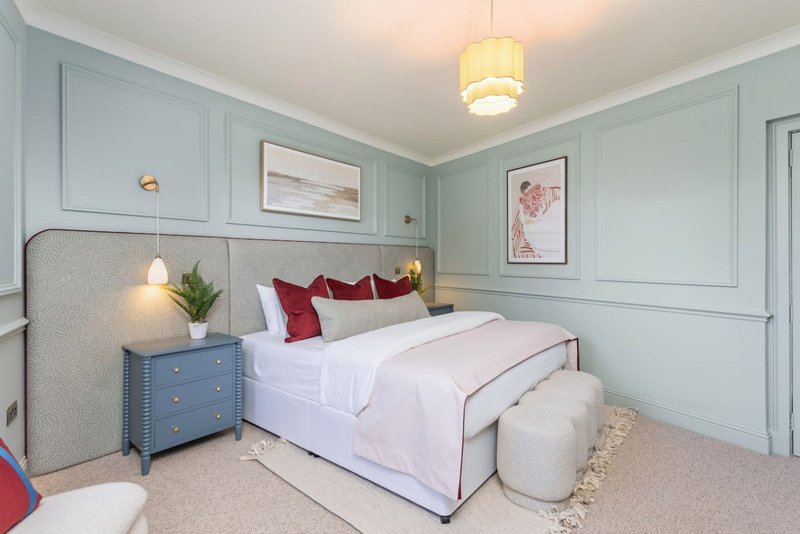 Modern bedroom with double bed, blue nightstand, pendant light and pale green panelled walls