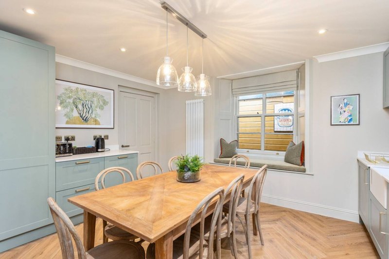 Modern kitchen-diner with wooden table, pendant lights, pale cabinetry and garden view