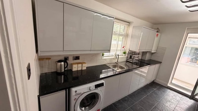 Modern kitchen with white cabinets, black countertop, integrated appliances and washing machine