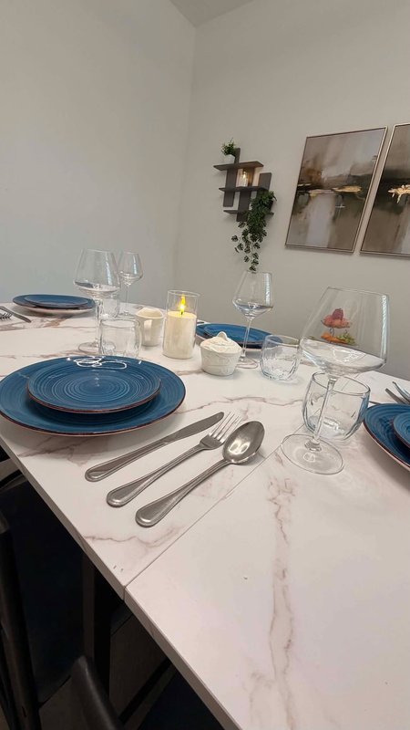 Dining table set with blue plates, glassware, cutlery and place settings