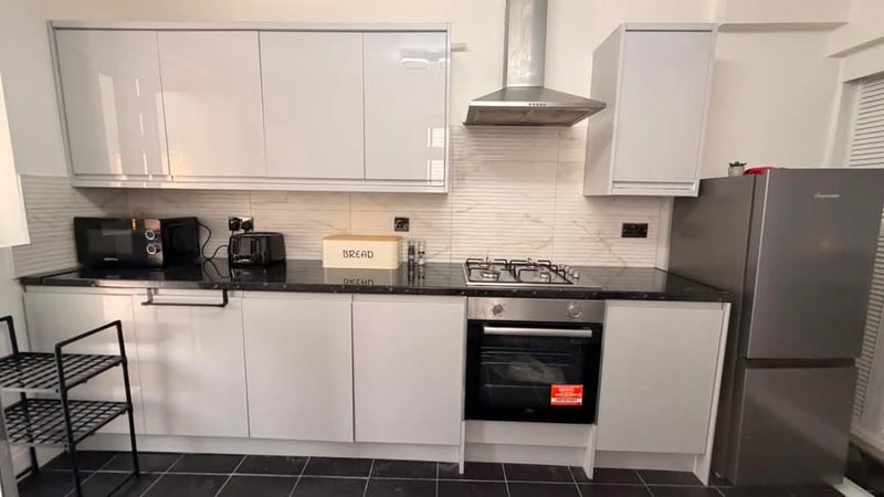 Modern kitchen with white cabinetry, black countertops, gas hob, and stainless steel appliances
