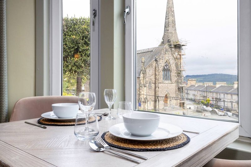 Dining table with place settings and view of church spire through large windows