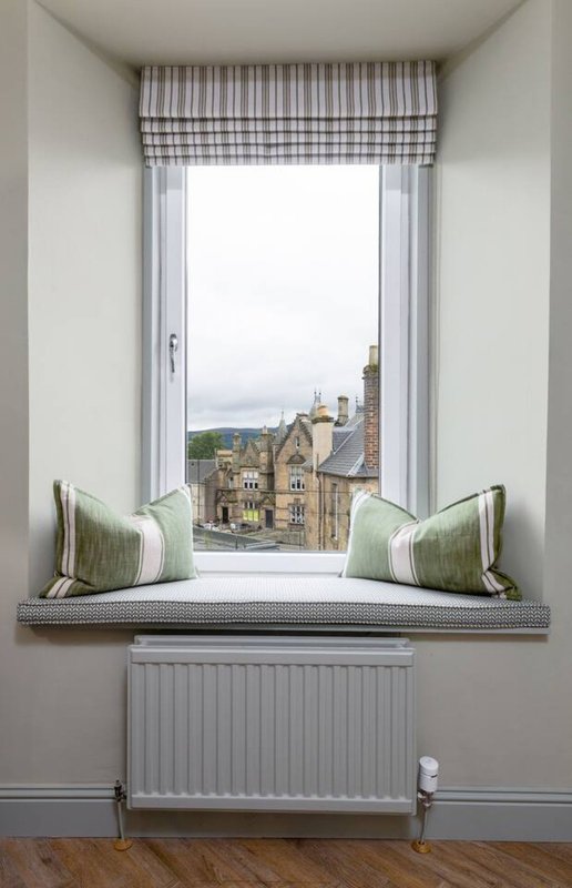 Window seat with cushions overlooking historic stone buildings and landscape view