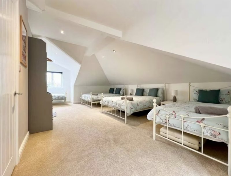 Bright attic bedroom with sloped ceiling, multiple single beds and neutral decor