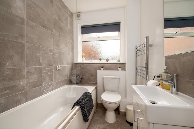 Modern bathroom with bathtub, toilet, sink, heated towel rail and window