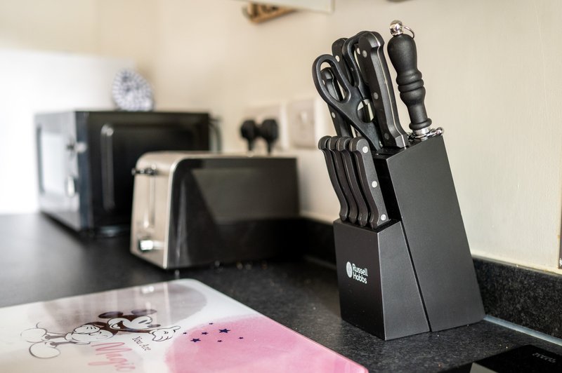 Kitchen countertop with knife block, small appliances, and pink notebook