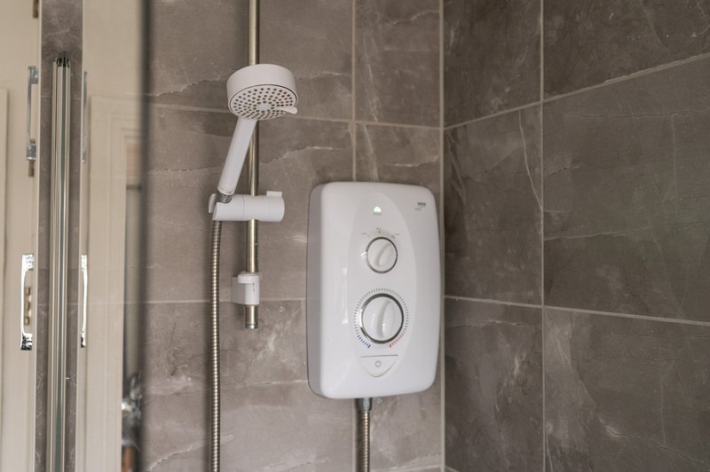 Modern bathroom shower with white electric heater unit and rainfall showerhead