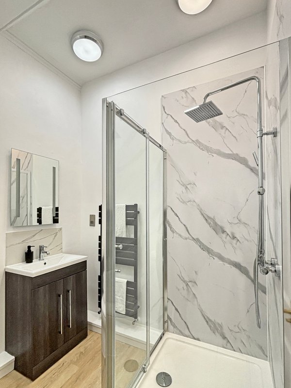Modern bathroom with marble shower enclosure, vanity sink, and recessed ceiling lights