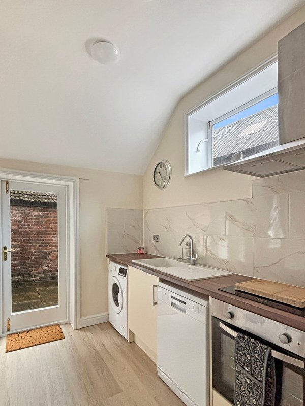 Modern kitchen with white units, wooden worktops, integrated appliances and window