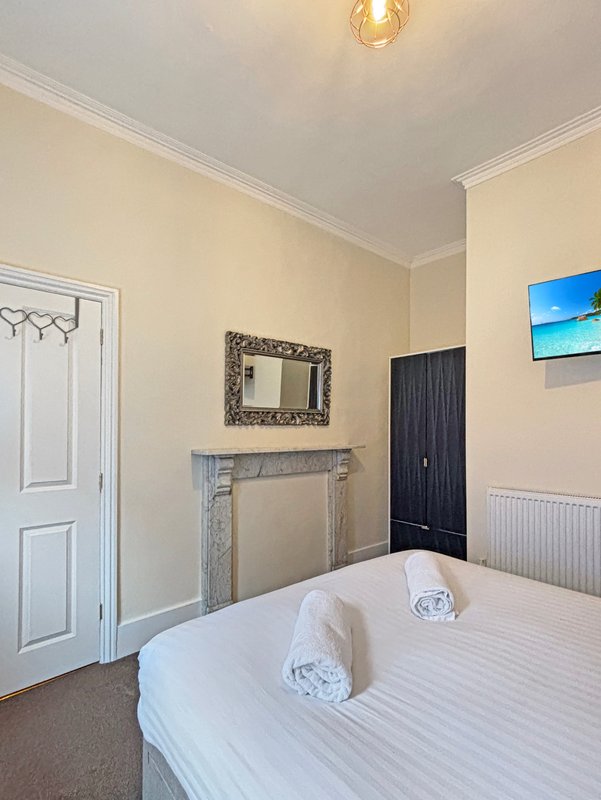Bedroom with double bed, fireplace, decorative mirror, and blue coastal wall art