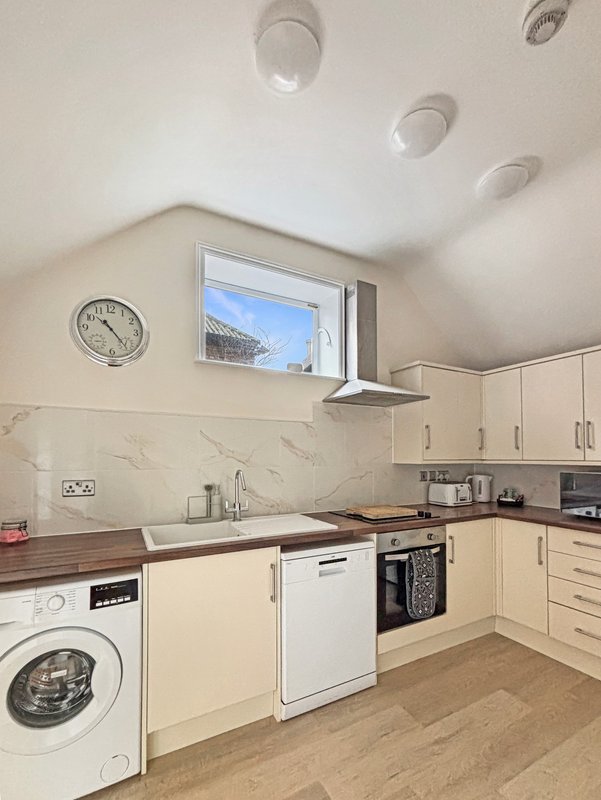 Modern kitchen with cream cabinetry, marble backsplash, integrated appliances and window view