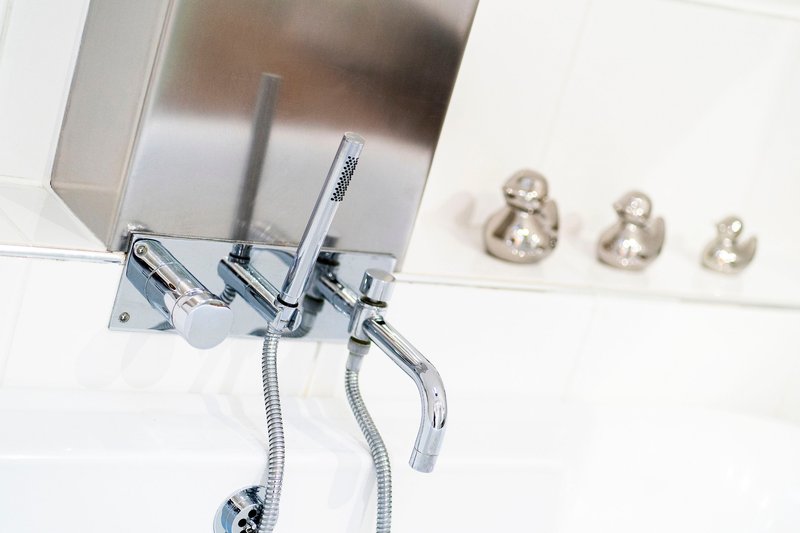 Modern bathroom wall-mounted faucet with chrome finish and decorative brass hooks
