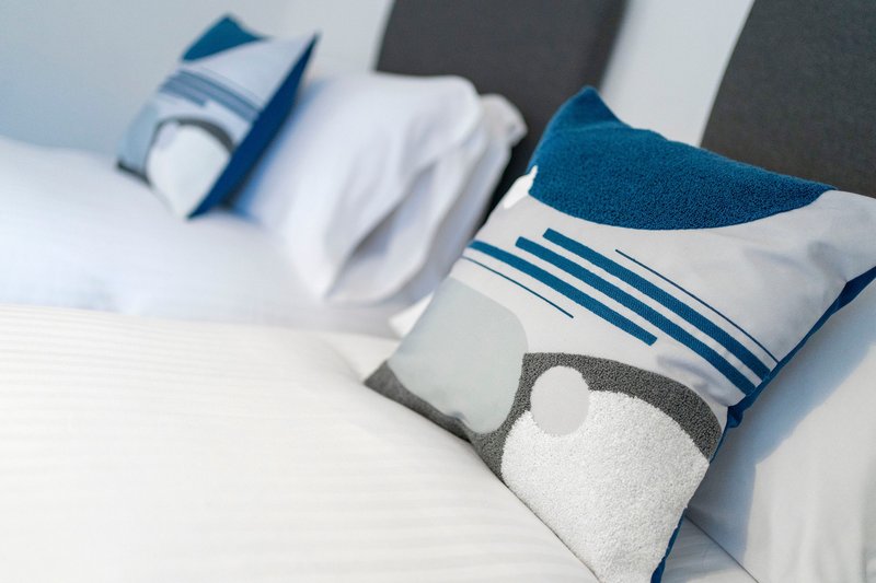 Bed with white sheets and blue striped decorative pillows