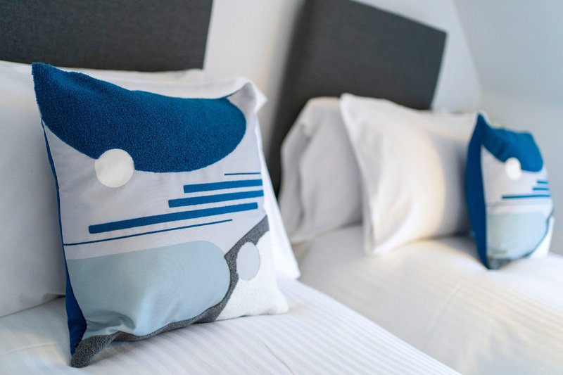 Bedroom with white bed, blue and white decorative pillows, and gray headboard