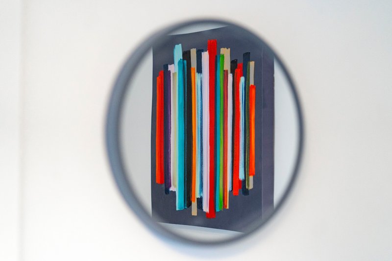 Modern wall-mounted abstract art with colorful vertical rods on dark background