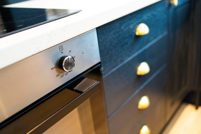 Modern kitchen detail with stainless steel oven and blue cabinetry with brass handles