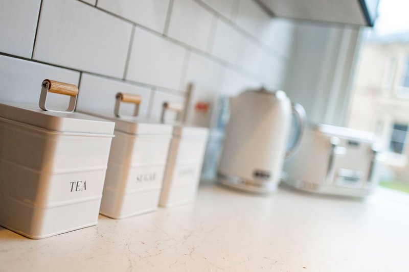 Kitchen counter with labeled storage containers, kettle and appliances by window