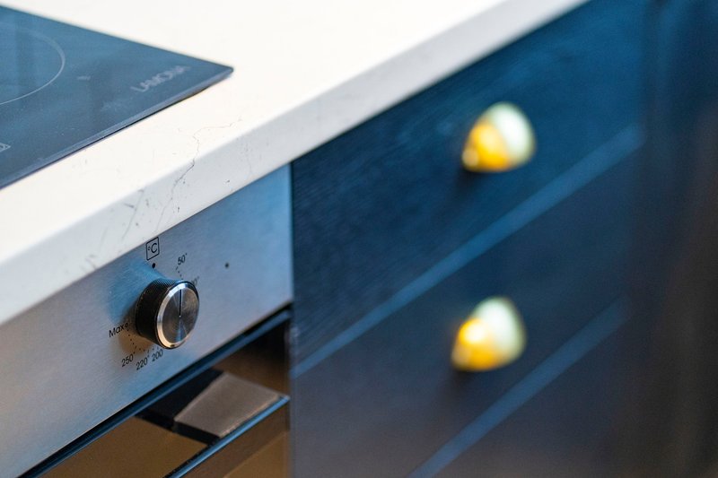 Close-up of blue kitchen cabinetry with illuminated knobs and stovetop edge