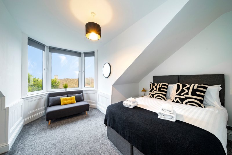 Modern attic bedroom with double bed, window seat, and sloped ceiling
