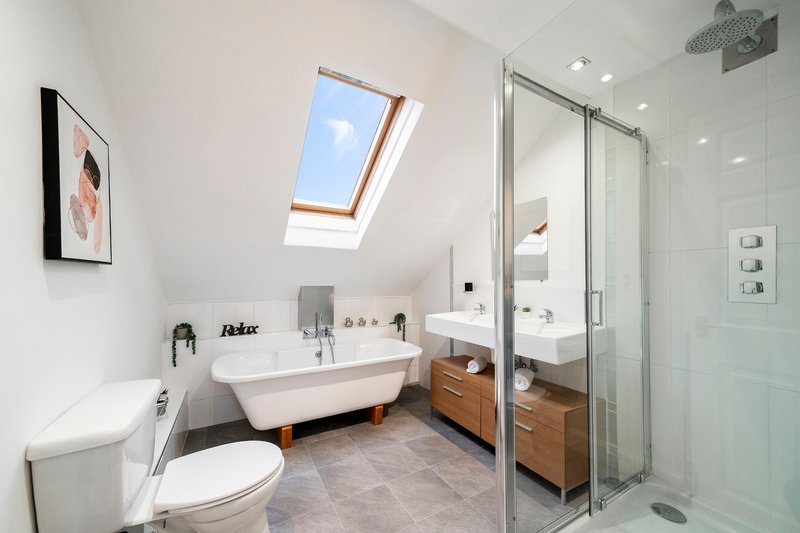 Modern bathroom with freestanding bathtub, walk-in shower, skylight and wooden vanity