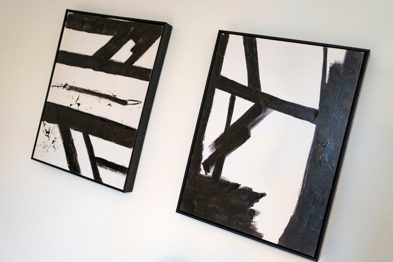 Two framed abstract black and white artworks hanging on white wall