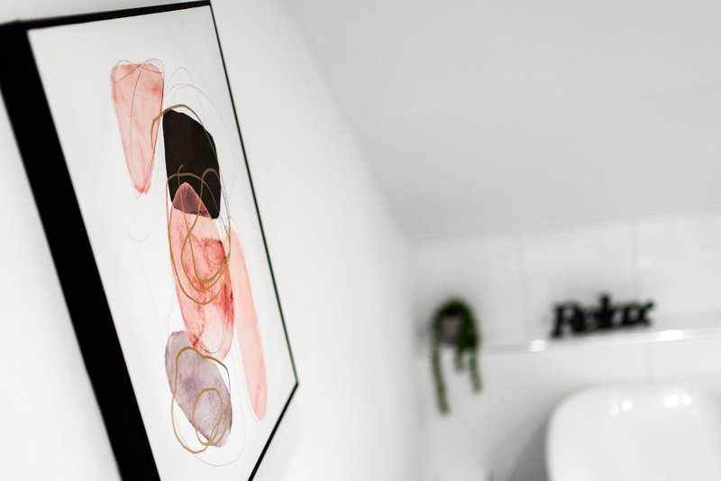 Framed abstract artwork with pink and black brush strokes on white wall