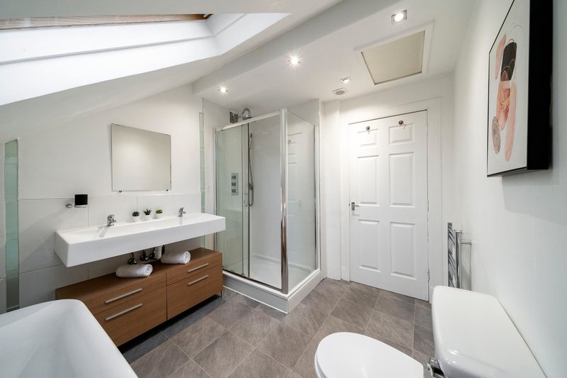 Modern bathroom with double vanity, walk-in shower, freestanding tub and skylight