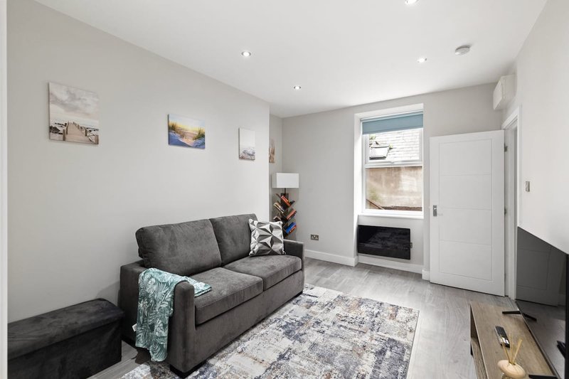 Modern living room with grey sofa, patterned rug, fireplace and framed wall art