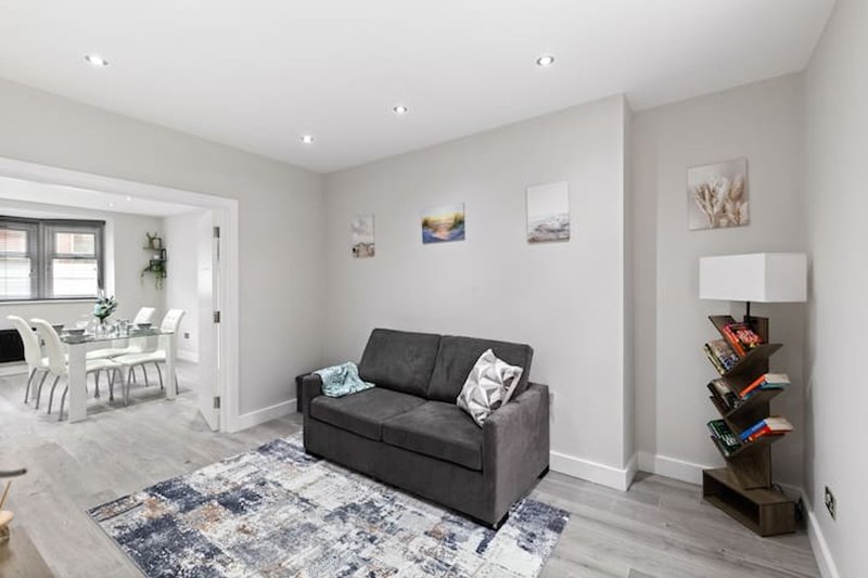 Modern living room with dark grey sofa, patterned area rug, and open-plan layout to dining area
