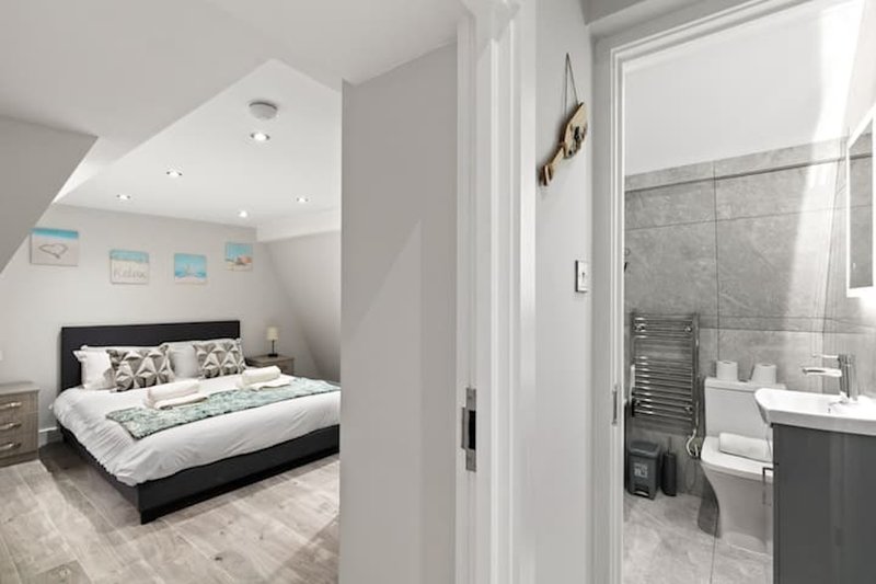 Bedroom with double bed, ensuite bathroom visible through open door, modern furnishings