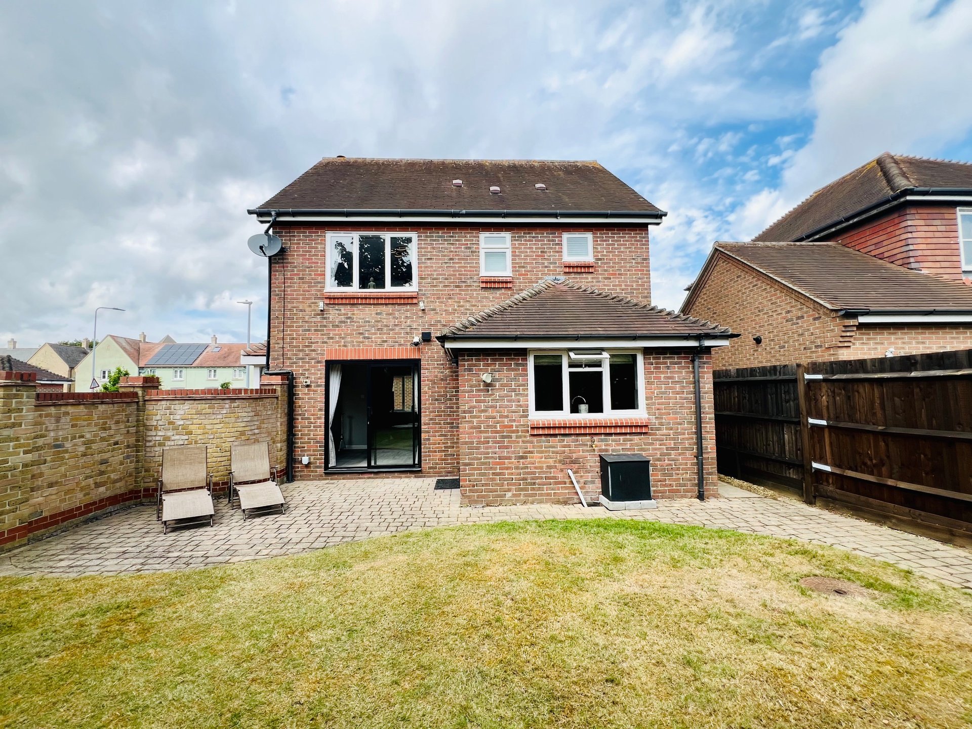 Brick detached house with garden, patio area and neighboring properties visible