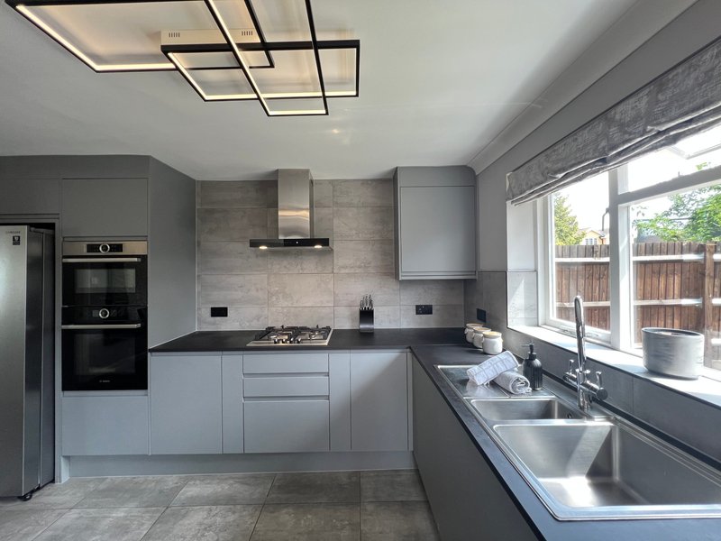 Modern kitchen with grey cabinetry, stainless steel appliances, island sink and garden view