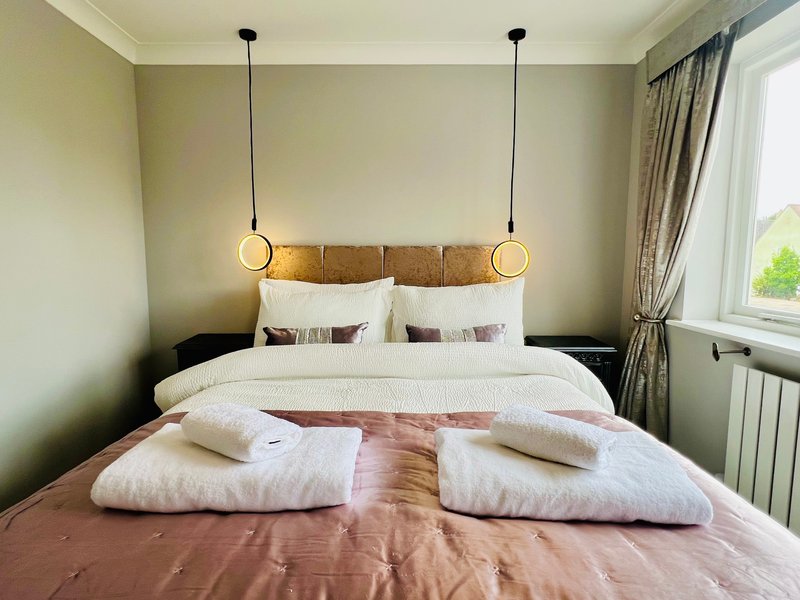 Bedroom with double bed, pendant lights, white bedding, and neutral-toned walls