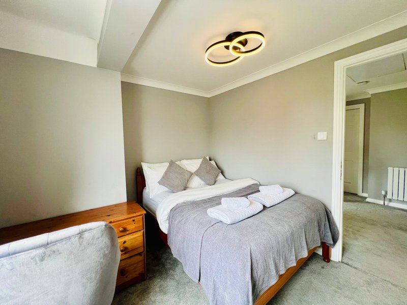 Bedroom with double bed, wooden nightstand, white pillows and gray bedding