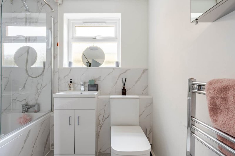 Modern bathroom with white vanity, marble-effect tiles, shower enclosure and heated towel rail