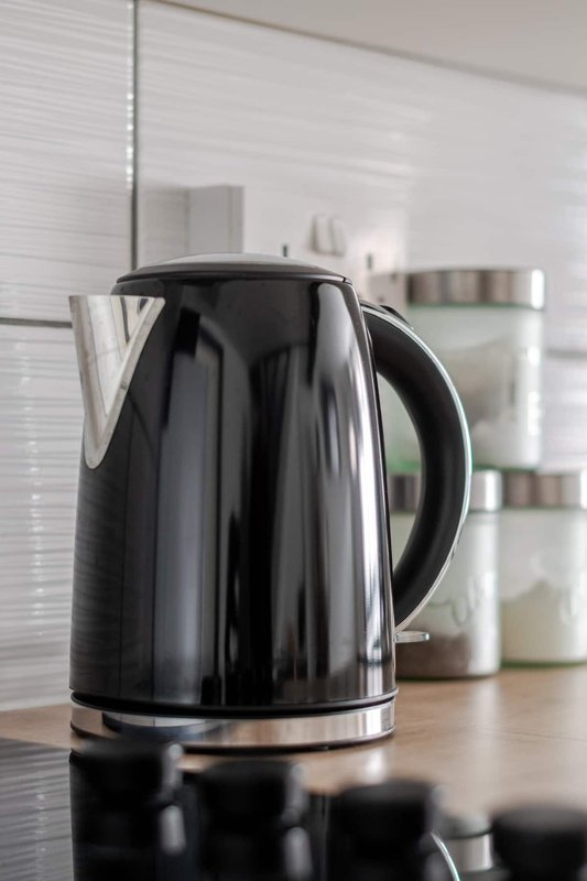 Black electric kettle on kitchen counter with white subway tile backsplash