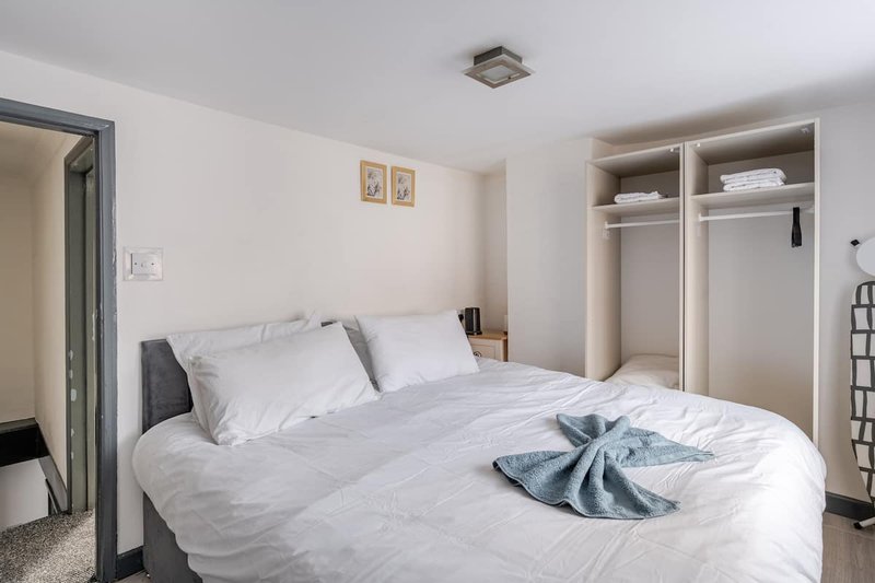 Bright bedroom with white bed, grey headboard, built-in wardrobe, and framed wall art