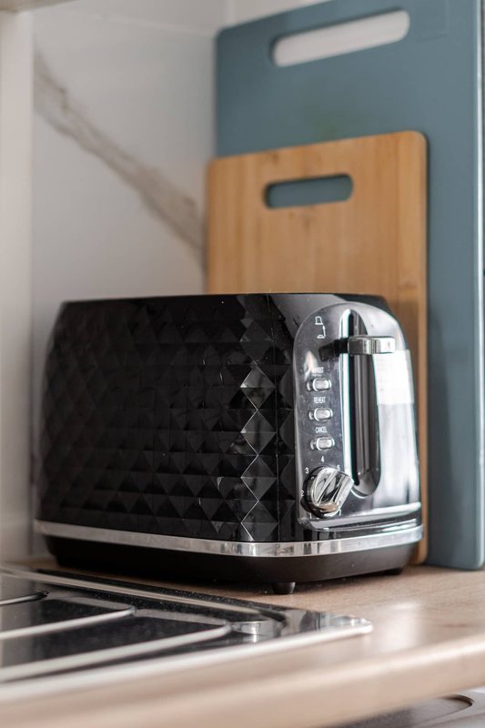 Kitchen counter with black toaster, wooden and blue cutting boards, and striped kitchen towel
