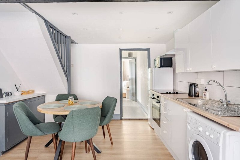 Open-plan kitchen and dining area with white cabinetry, wooden worktops, round dining table and green chairs