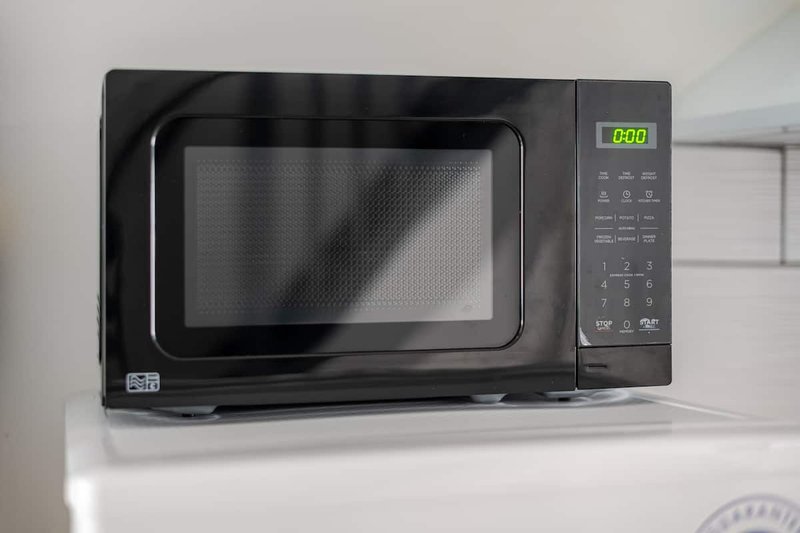 Black microwave oven on white kitchen counter with digital display