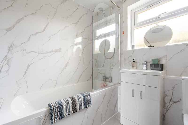 Modern bathroom with marble-effect tiles, walk-in shower, white vanity and mirror