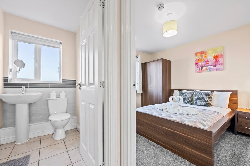 Bedroom with double bed and wooden furniture, adjoining bathroom with sink and toilet